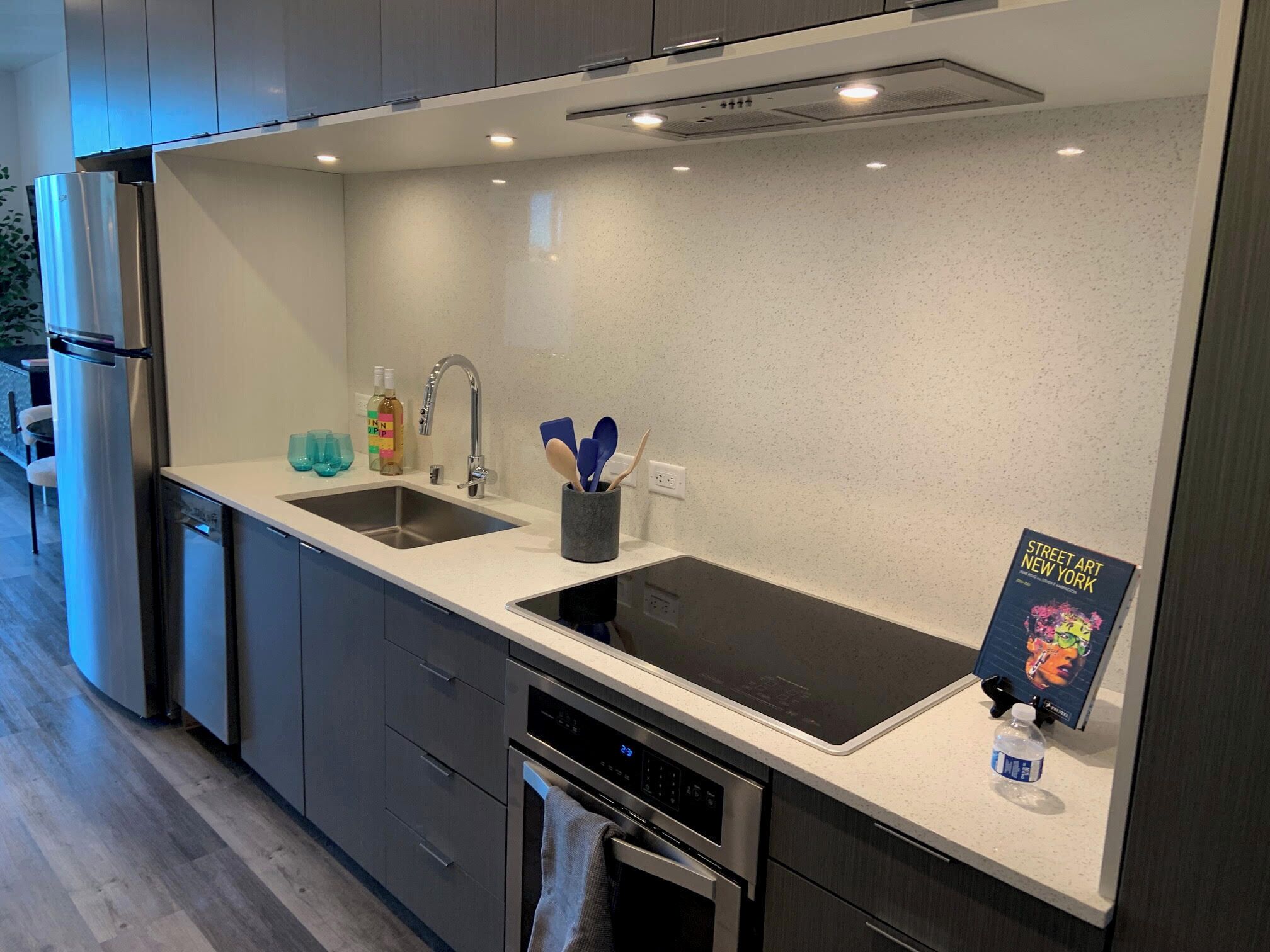 Una cucina moderna con elettrodomestici in acciaio inossidabile, un lavello doppio e un libro intitolato "Street Art New York" sul piano di lavoro.