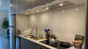 A modern kitchen with a stainless steel refrigerator, a built-in oven, a sink with a faucet, and a kettle on the stove. - Stylish Midtown of Sacramento Luxurious and Spacious Studio at level 6 nice view (Sacramento)