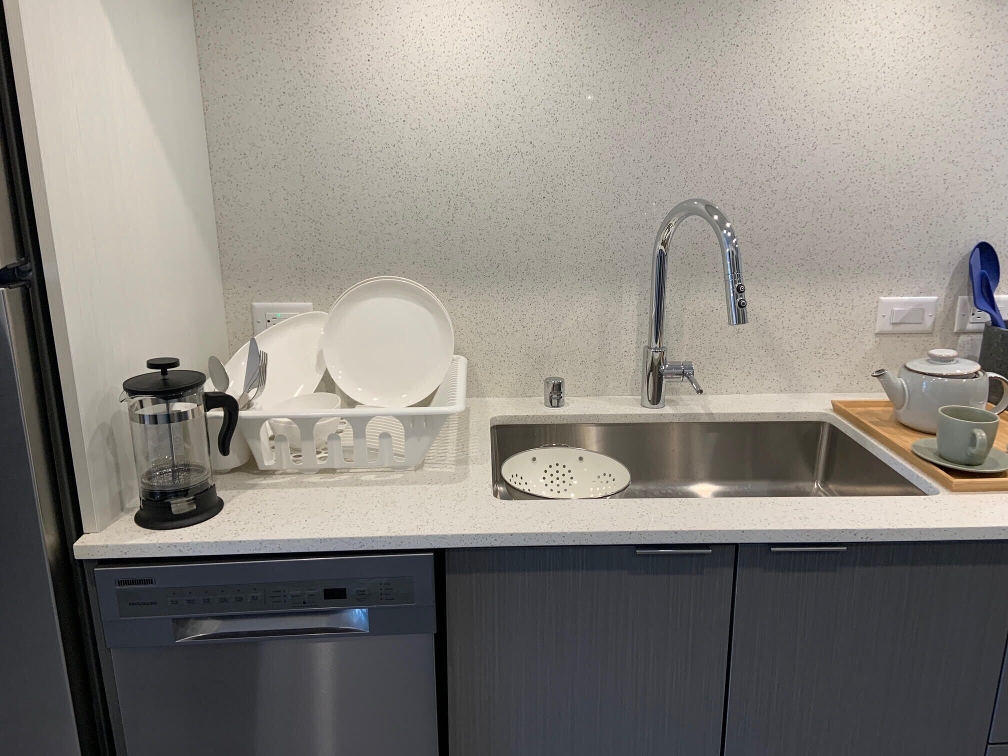 Een moderne keuken met een roestvrijstalen spoelbak, een koffiezetapparaat en een afwassysteem.