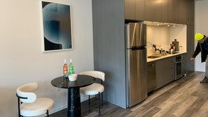 A modern kitchen with stainless steel appliances, a dining area with a round table and chairs, and a large abstract painting on the wall. - Stylish Midtown of Sacramento Luxurious and Spacious Studio at level 6 nice view (Sacramento)