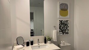 A modern bathroom with a large mirror, a sink, a toilet, and two abstract wall art pieces. - Stylish Midtown of Sacramento Luxurious and Spacious Studio at level 6 nice view (Sacramento)
