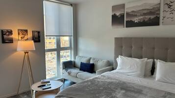 A bedroom with a bed, a sofa, a round table, and a floor lamp.