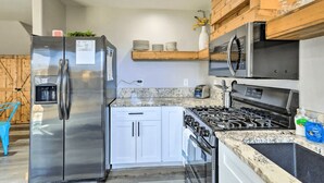 Une cuisine moderne dotée d’appareils électroménagers en acier inoxydable, de meubles blancs et d’un plan de travail en granit.