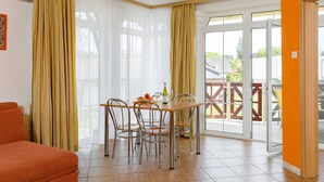 Un espace repas comprenant une table et des chaises, un canapé et une porte-fenêtre coulissante donnant sur un espace extérieur.