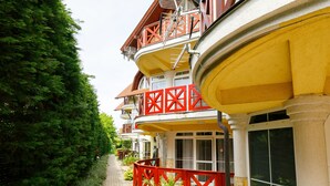 Un immeuble à plusieurs étages doté de balcons, d’un chemin et d’une clôture rouge.