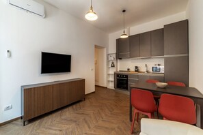 Een moderne keuken met een flatscreen televisie, een ingebouwde oven, magnetron en een eethoek met rode stoelen.