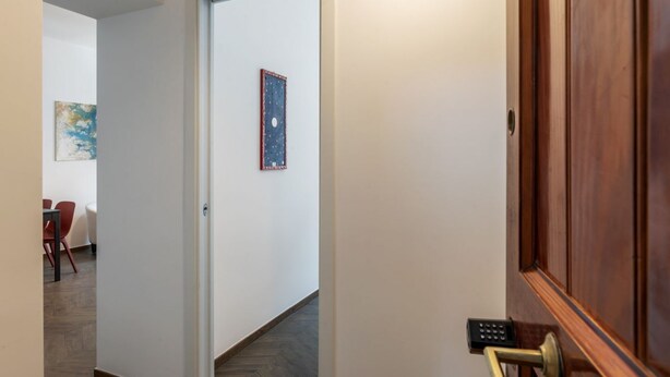 A hallway with a wooden door, a small table with chairs, and a framed picture on the wall. - Testaccio 11 - FromHometoRome (Roma)