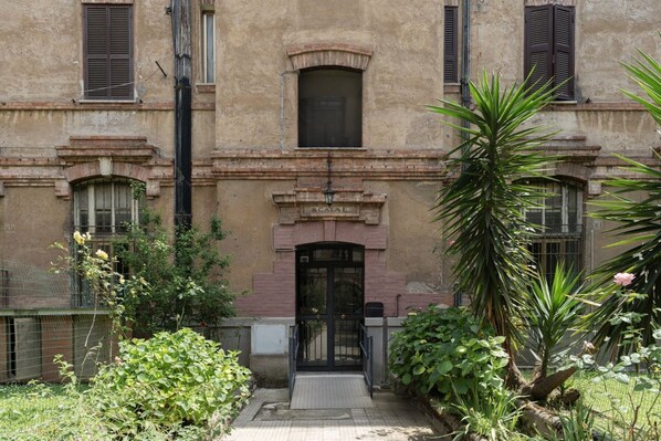 A building with a central entrance, a sign reading "SCALA", and a small window above the door.