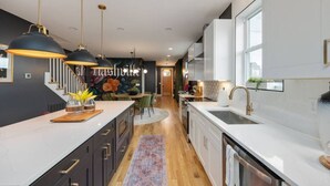 A modern kitchen with white cabinetry, black pendant lights, and a central island.