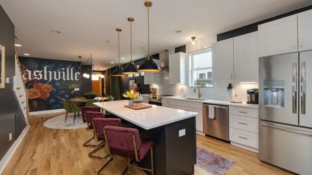 A modern kitchen with a central island, stainless steel appliances, and a mural on the wall.