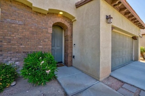 A residential building with a brick facade, a grey door, and a garage.