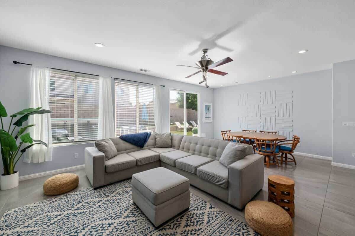 A modern living room with a sectional sofa, ottoman, and a dining area with a table and chairs.