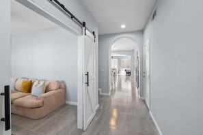 Ein modernes Interieur mit einem beigen Sofa, einer Schiebetür und einem Flur, der in einen weiteren Raum führt.