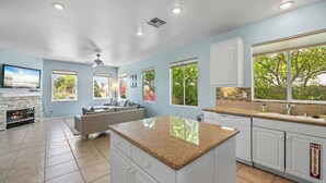A spacious kitchen with white cabinets, a granite countertop, and a large window overlooking a garden. - Private Pool & Hot Tub | Indian Palms 3BR (Indio)