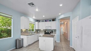 A modern kitchen with white cabinets, a granite countertop, and a built-in microwave. - Private Pool & Hot Tub | Indian Palms 3BR (Indio)