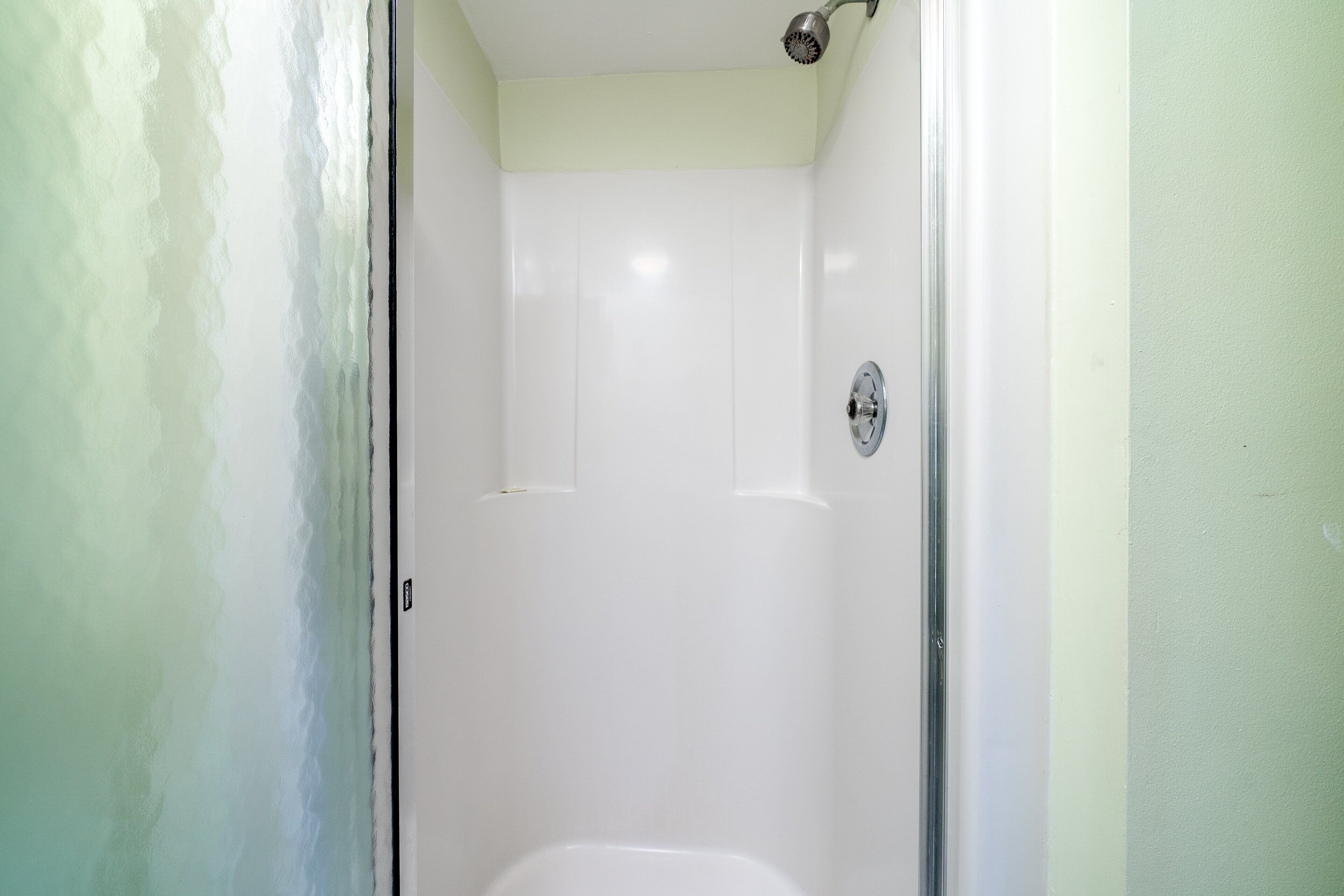 A small, enclosed shower area with a door and a showerhead.