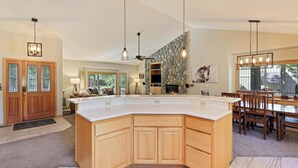 A spacious kitchen with a large island, wooden cabinets, and pendant lighting. - 37 Kinglet - North End River Charmer! Hot Tub, SHARC, Ping Pong, Bikes (Sunriver)