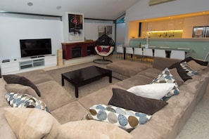 Ein modernes Wohnzimmer mit einer großen Eckcouch, einem Flachbildfernseher und einem Kamin.