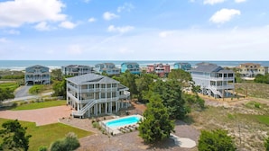 Un área residencial costera con varias casas de dos pisos, una piscina y vista al océano.
