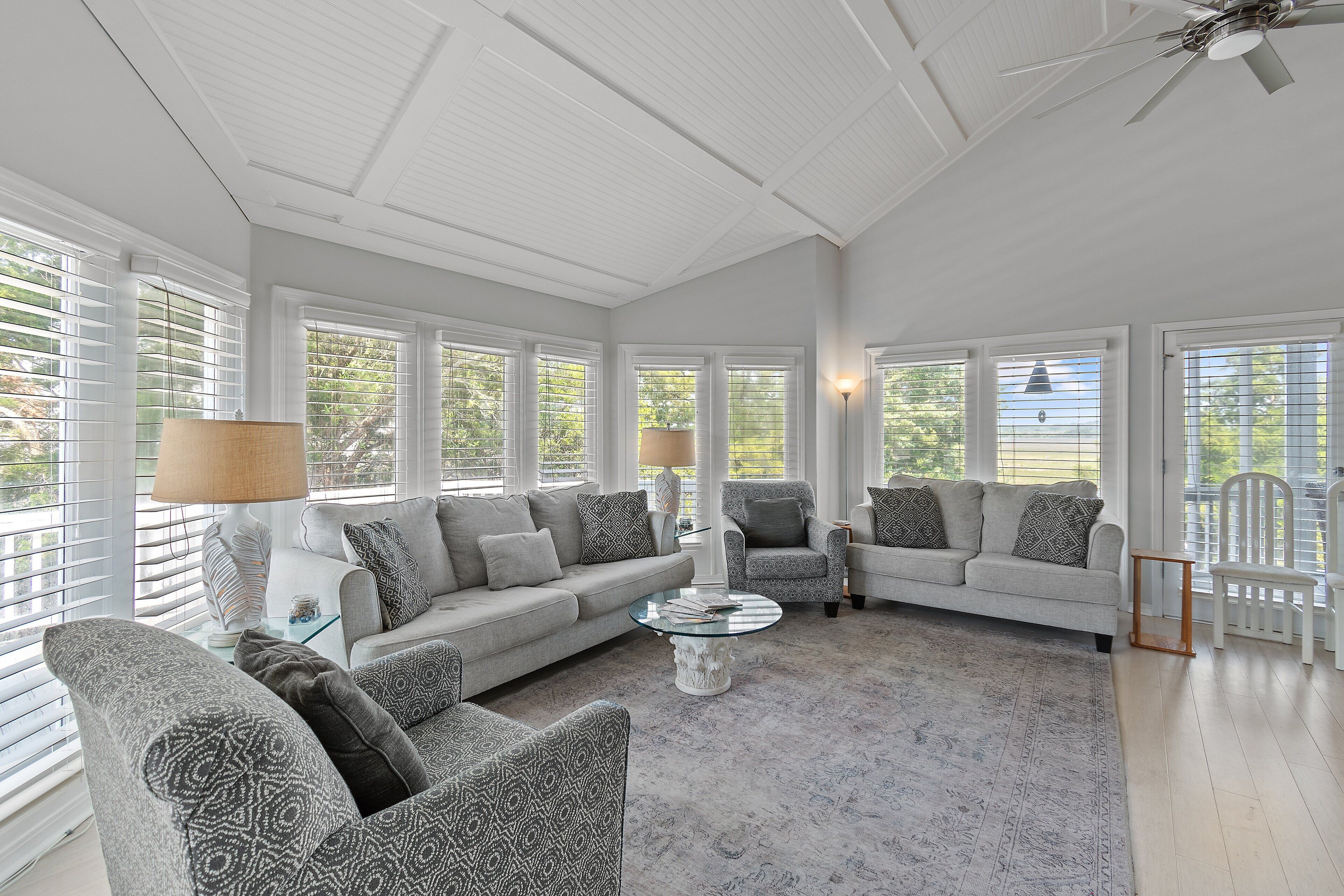 Un salon spacieux comprenant un grand canapé, deux fauteuils, une table basse et un ventilateur de plafond.