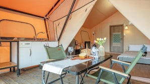 A cozy, triangular tented room with a kitchenette, a dining table with chairs, and a bed. - Gapyeong Sanmaeul Glamping (Gapyeong)