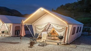A large, well-lit tent with a dining area inside, surrounded by gravel. - Gapyeong Sanmaeul Glamping (Gapyeong)
