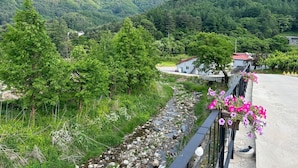 A rural landscape with a road, a stone wall, and a house with a red roof. - Gapyeong Sanmaeul Glamping (Gapyeong)