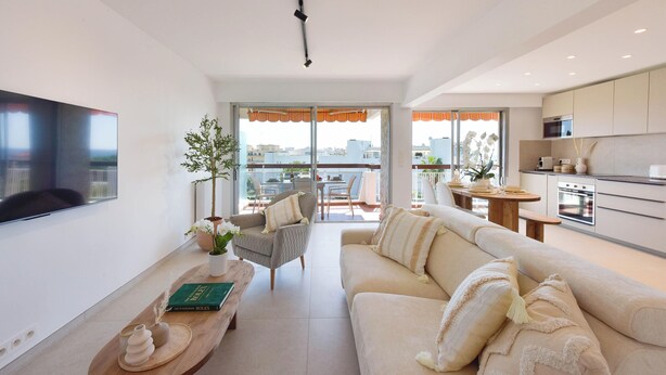 A modern living room with a sofa, armchair, and coffee table, a flat-screen TV, and a view to the outside. - Luxury 1-Br. apartment, sea view, parking. (Vallauris)