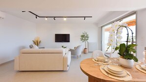 A modern living room with a sofa, a dining table set for two, and a large window with a view. - Luxury 1-Br. apartment, sea view, parking. (Vallauris)