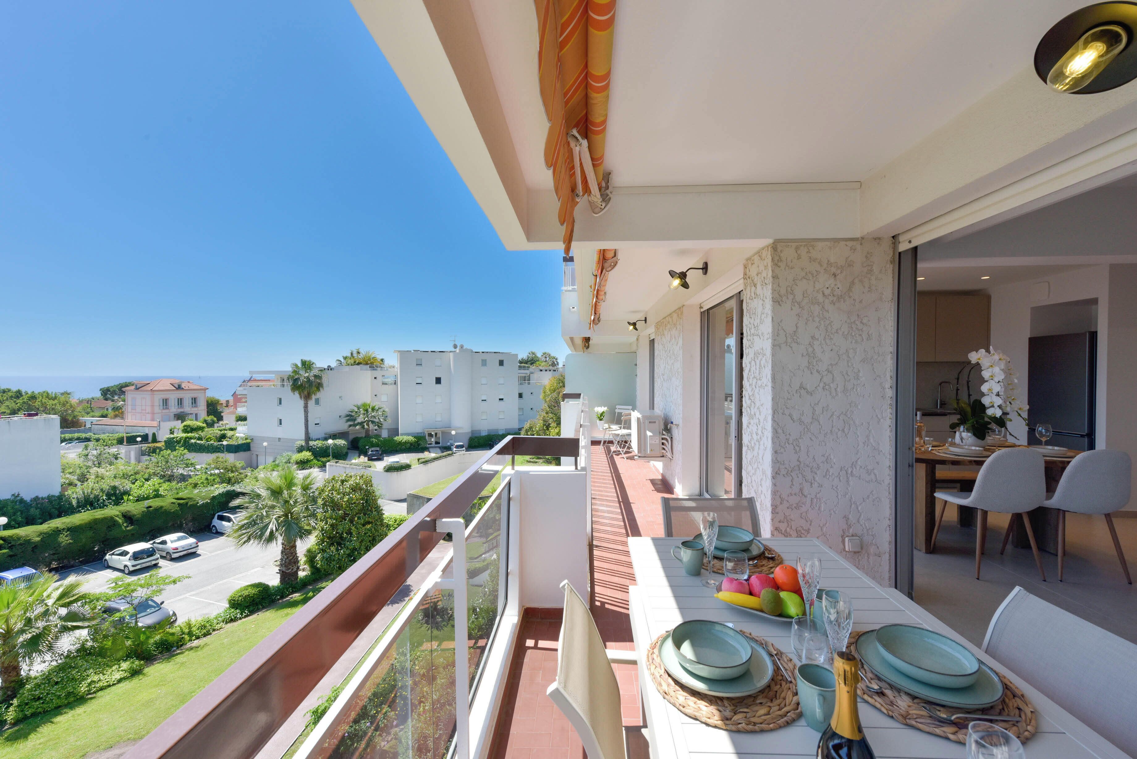 A balcony with a dining setup overlooking a residential area and the sea.