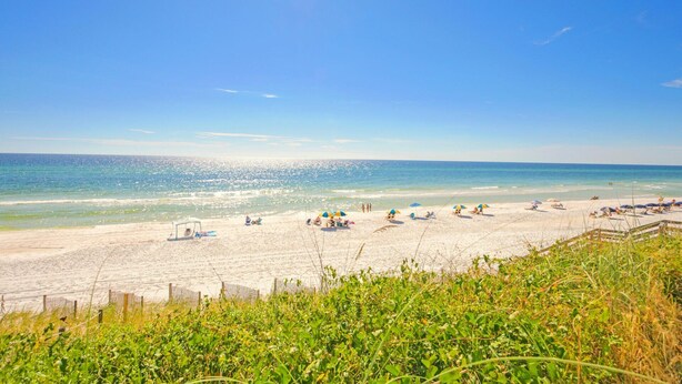 Een strand met een zandstrand, helderblauwe lucht en een rustige zee.