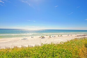 A beach with a sandy shore, clear blue sky, and calm sea.