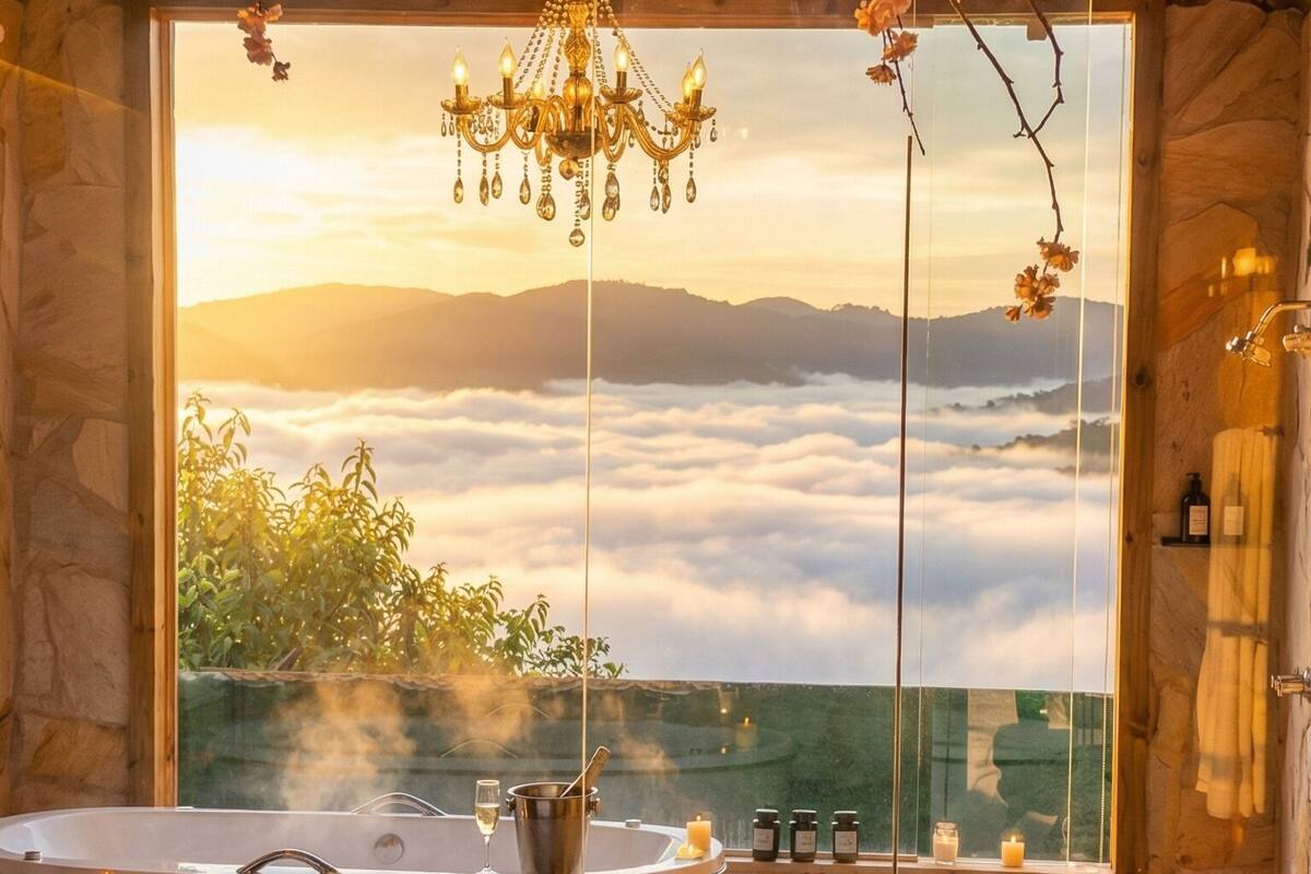 A bedroom with a large window, a bathtub, and a bed with rose petals.