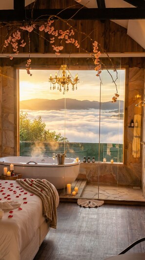 Une chambre avec une grande fenêtre, une baignoire et un lit parsemé de pétales de rose.