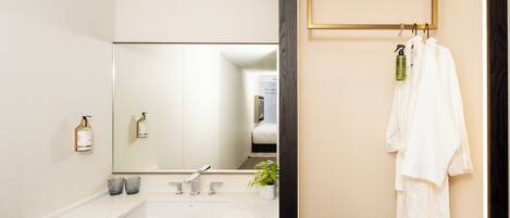 A bathroom with a large mirror, a sink, and a towel rack.