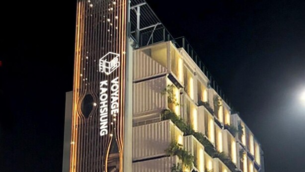 Un hotel moderno con una fachada singular que presenta líneas verticales y el nombre "Voyage Kaohsiung" iluminado en el lateral.