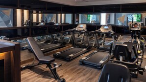 Un gimnasio con cintas de correr, bicicletas estáticas y máquinas de pesas.