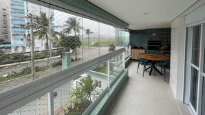 Een balkon met uitzicht op een woonwijk, een kleine keuken met een eettafel en stoelen, en een betegelde spatwand.