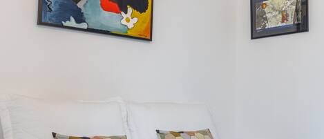 Un dormitorio con una cama, dos almohadas, un edredón y dos obras de arte en la pared.