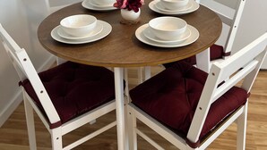 Una mesa redonda de comedor con sillas blancas y un florero con flores.
