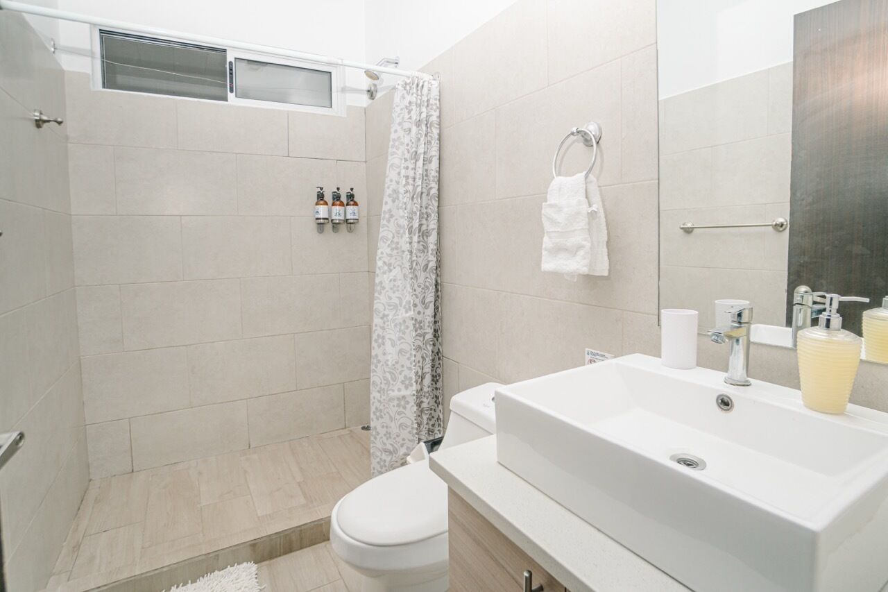 A modern bathroom with a shower, toilet, and sink.