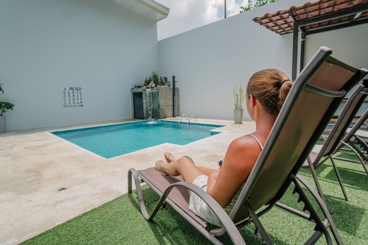 A poolside area with a lounge chair, a small pool, and a 'POOL RULES' sign on the wall.