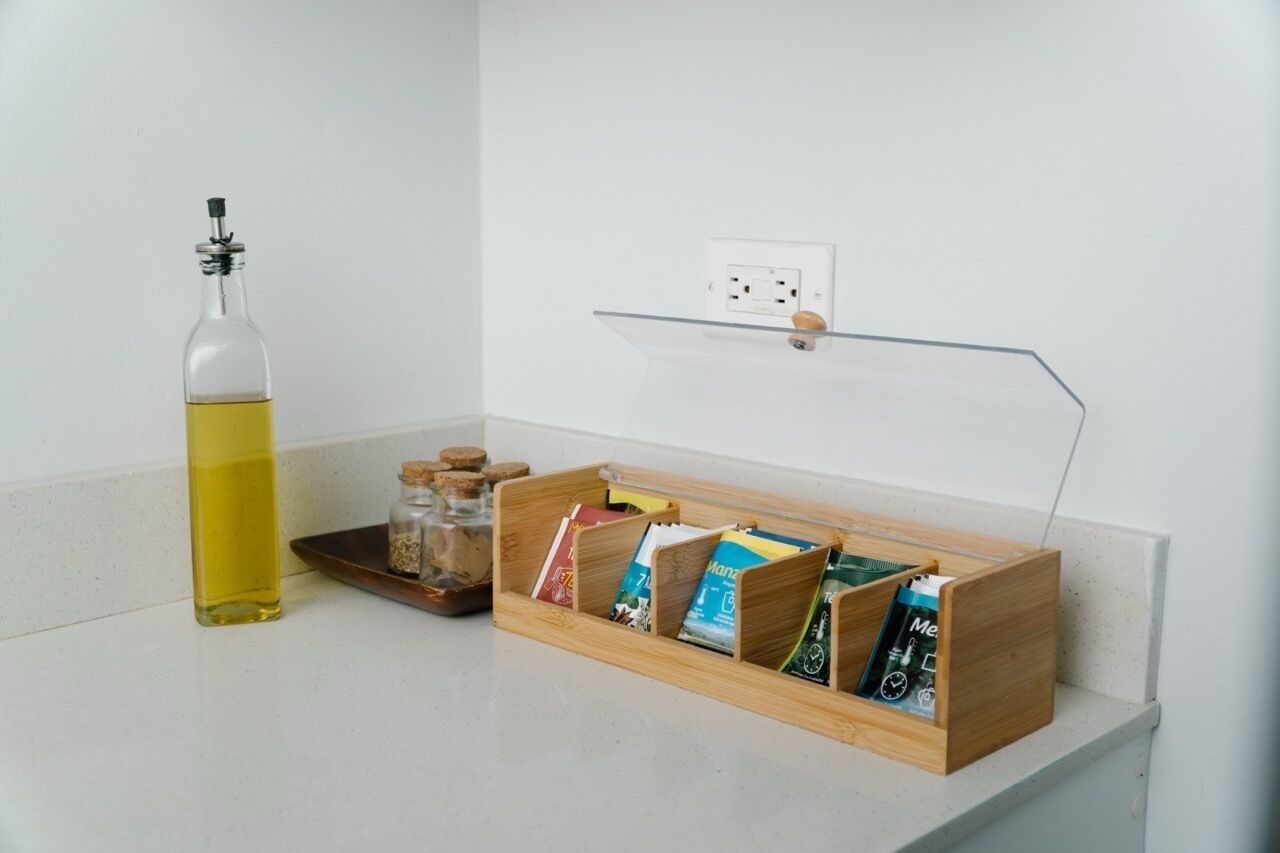 Un plan de travail de cuisine avec une bouteille d’huile, un étagère à épices et une boîte en bois contenant des sachets.