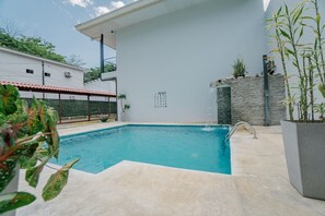 A swimming pool with a stone wall and a metal ladder.