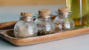 Tres botellas de vidrio con tapones de corcho sobre una bandeja de madera.