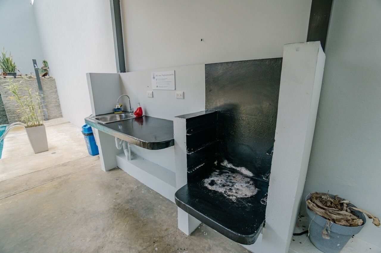 A compact outdoor kitchen area with a sink, a built-in grill, and a small seating area.