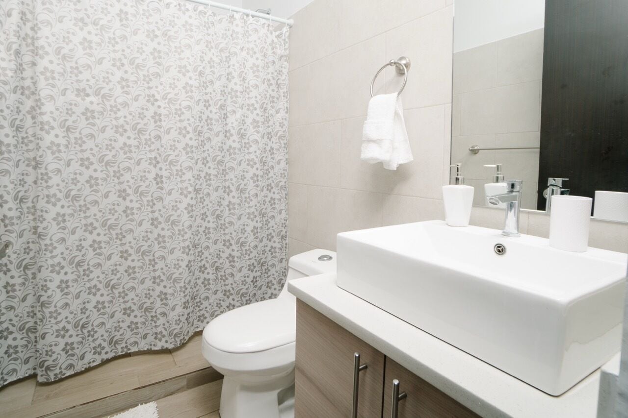 A bathroom with a toilet, a white sink with a mirror, and a shower curtain with a floral pattern.