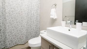 A bathroom with a toilet, a white sink with a mirror, and a shower curtain with a floral pattern.