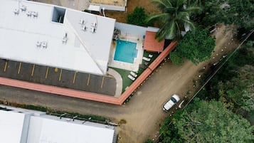 Ein Luftbild eines Gebäudes mit Schwimmbecken, Parkplatz und einem Gebäude mit rotem Dach.