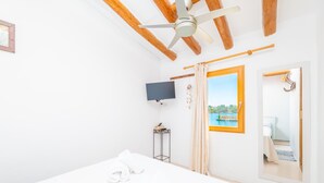 Habitación de hotel con cama, ventilador de techo, televisor, ventana con vista a una piscina y espejo.